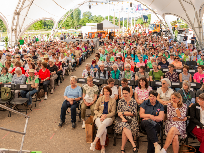 Große sitzende Menschenmenge unter einem Zeltdach
