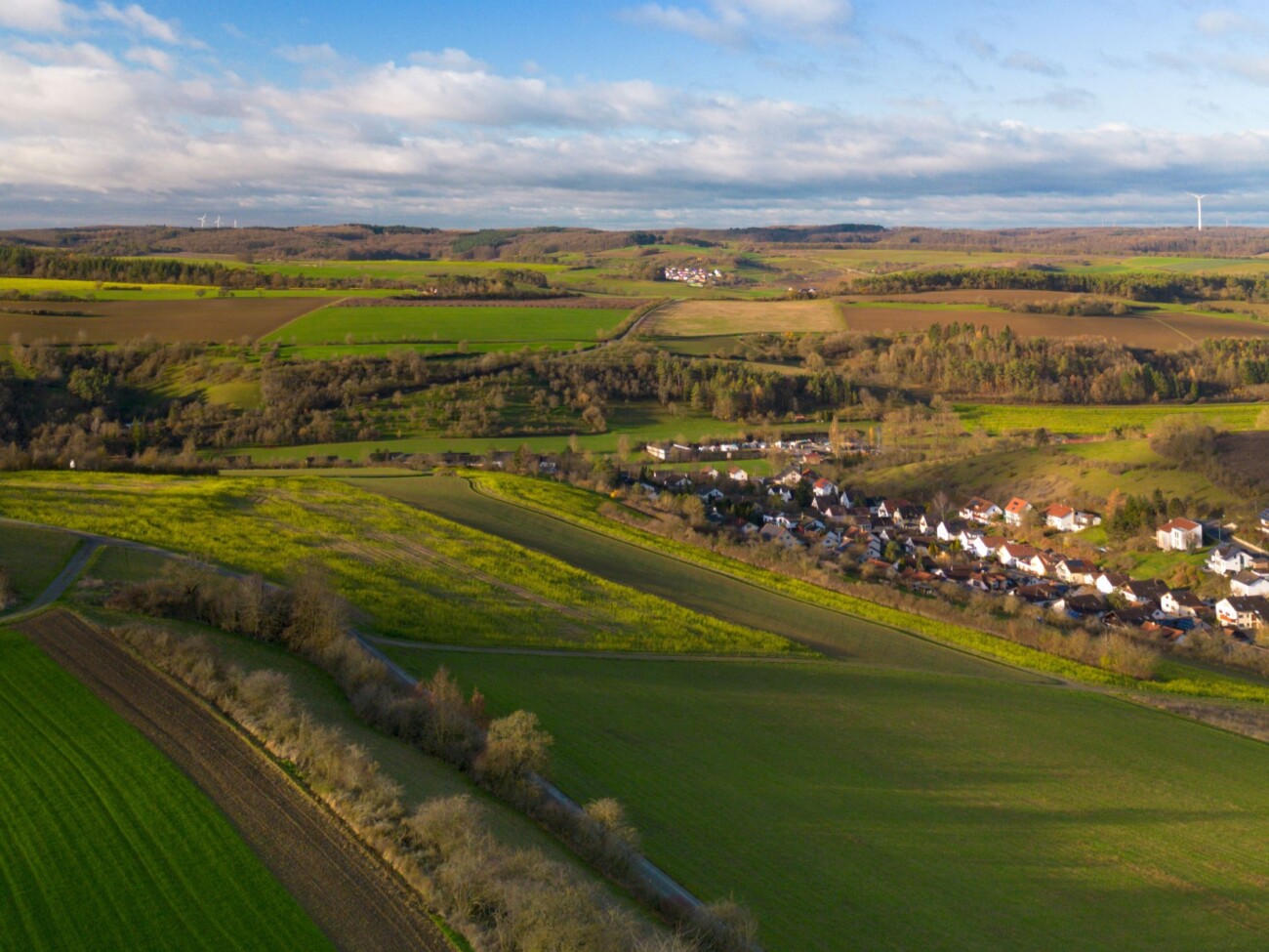 Eine lebendige Luftaufnahme der Landschaft in der Nähe von Bad Mergentheim mit üppigen grünen Feldern und einem klaren blauen Himmel