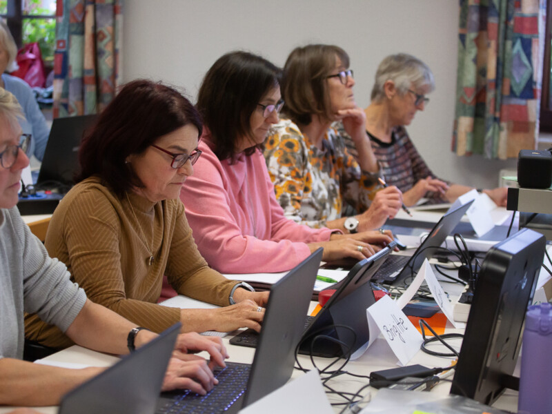Fünf Frauen sitzen vor Laptops