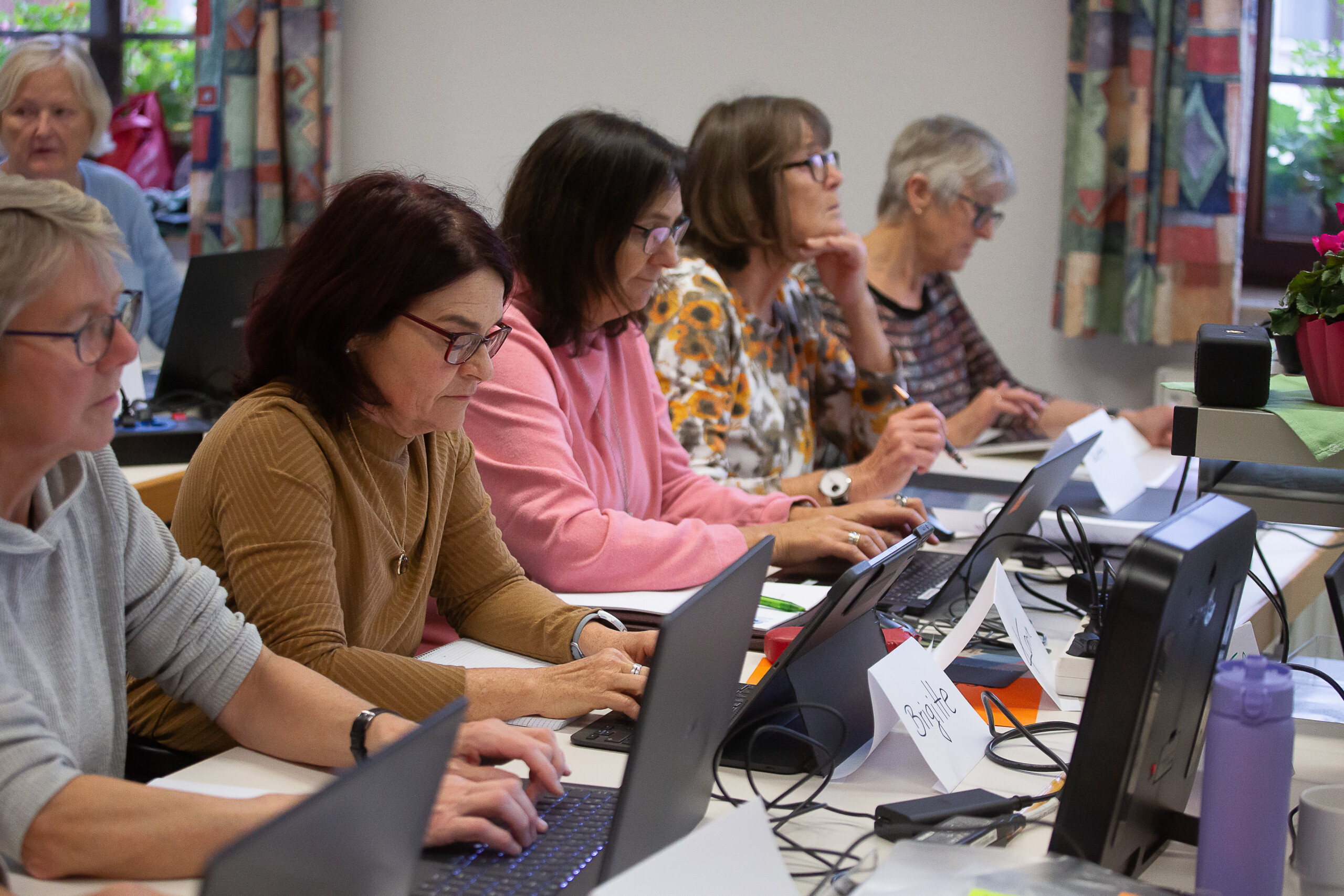 Fünf Frauen sitzen vor Laptops