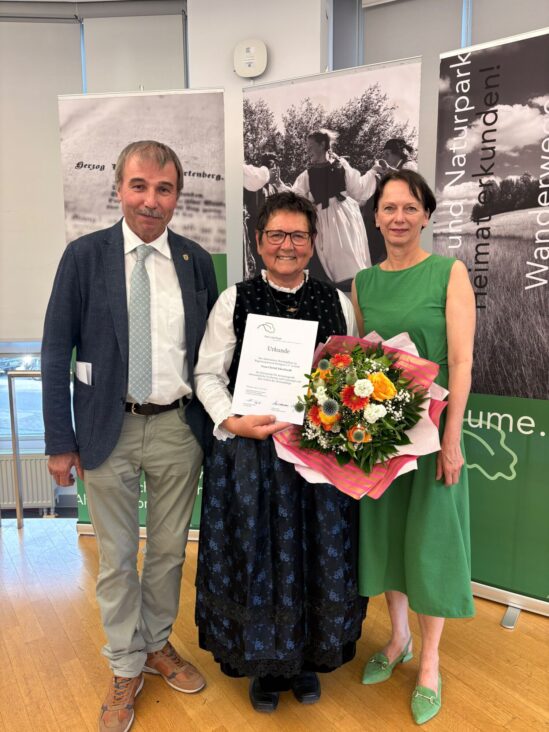 Geehrte LandFrau in der Mitte mit Blumenstrauß und Urkunde, links daneben Konrad Epple MdL, Links daneben Regierungspräsidentin Susanne Bay