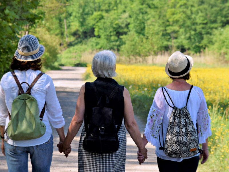 Drei Frauen in einer Reihe von hinten, die sich an den Händen halten